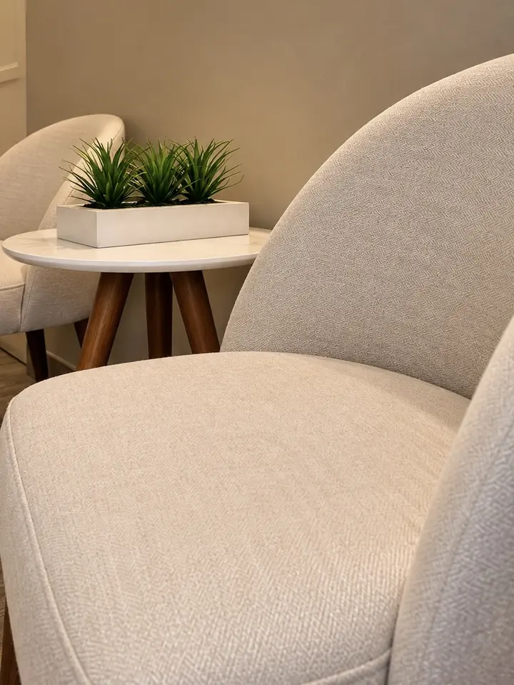 Sillón claro con cojines en la sala de espera de Eunoia Spa.
